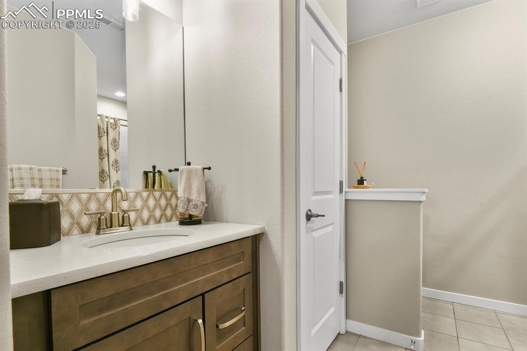 Image 40 of 50: Bathroom featuring vanity, light tile patterned flooring, tasteful backspla