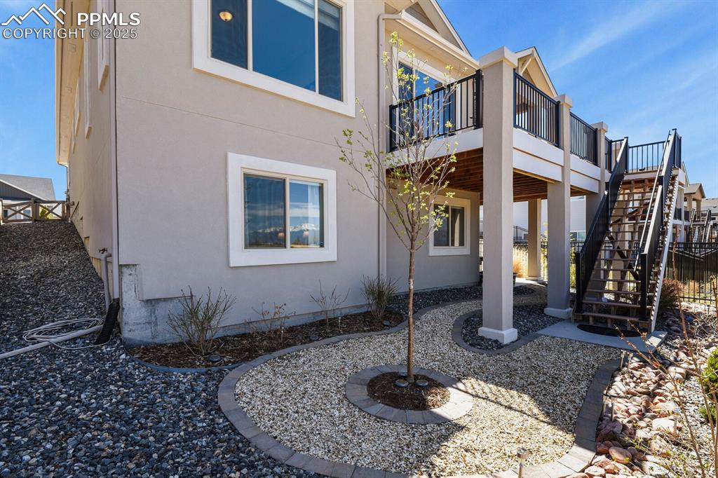 Image 46 of 50: Rear view of house featuring a patio, stairs, stucco siding, and a deck