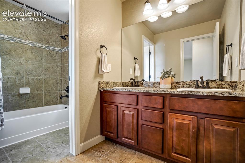 Image 31 of 47: Full secondary bathroom upstairs has dual sinks, granite counters, and a se