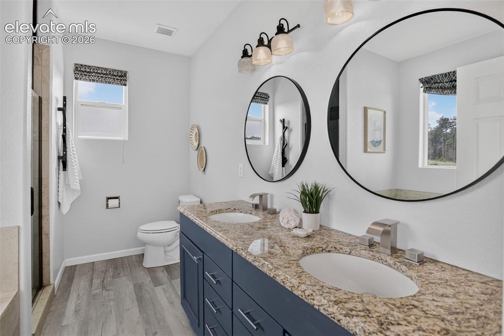 Image 22 of 50: Primary bathroom with double sink granite countertops.