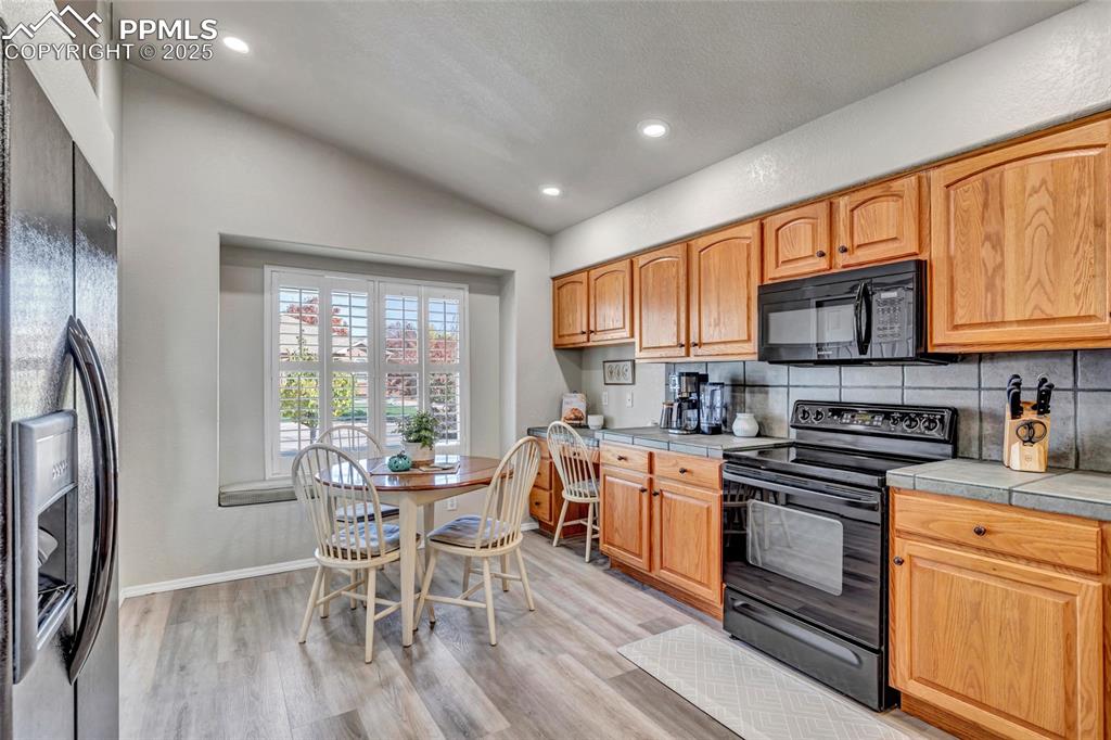 Image 7 of 23: Bright and functional kitchen with abundant cabinetry, tile counters, and a