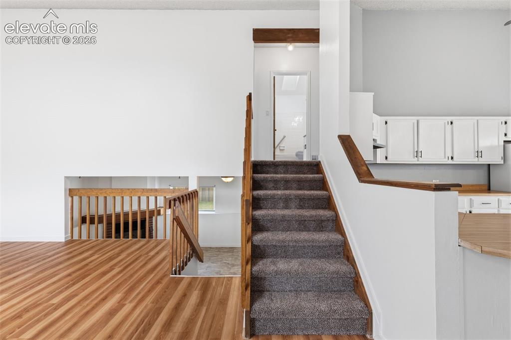 Image 17 of 43: Multi-level interior featuring wood-finish flooring, a carpeted staircase w