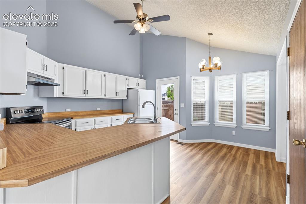 Image 19 of 43: Kitchen featuring white cabinetry, wood-finish countertops, and an electric
