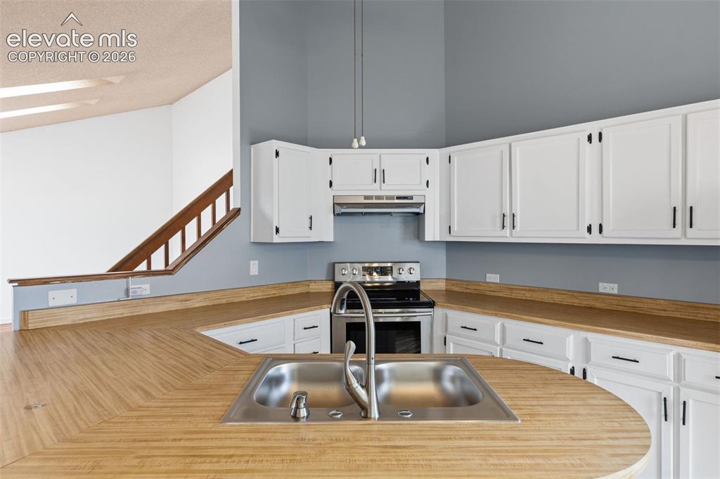Image 22 of 43: Kitchen featuring white cabinetry, wood-finish countertops, stainless steel