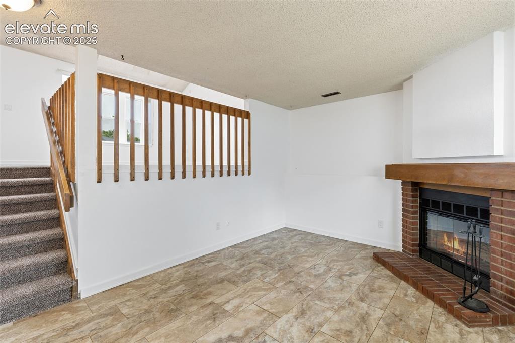 Image 26 of 43: Open concept living area featuring a brick fireplace with a wood mantle, ti