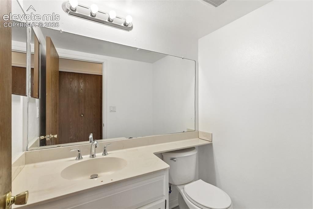 Image 28 of 43: Compact bathroom featuring a white vanity with integrated sink, chrome fauc