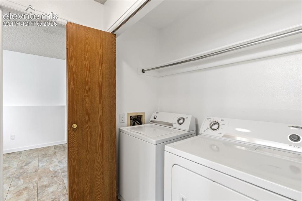 Image 29 of 43: Dedicated laundry area featuring a washer and dryer, tile flooring, a wall-