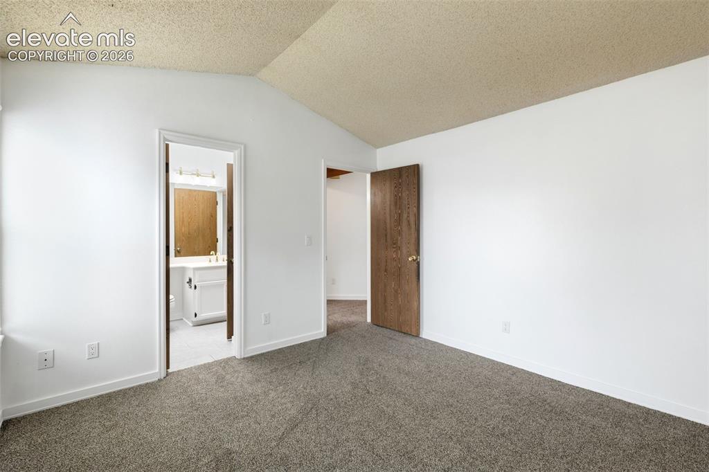 Image 34 of 43: Vaulted ceiling bedroom with neutral carpeting and white painted walls