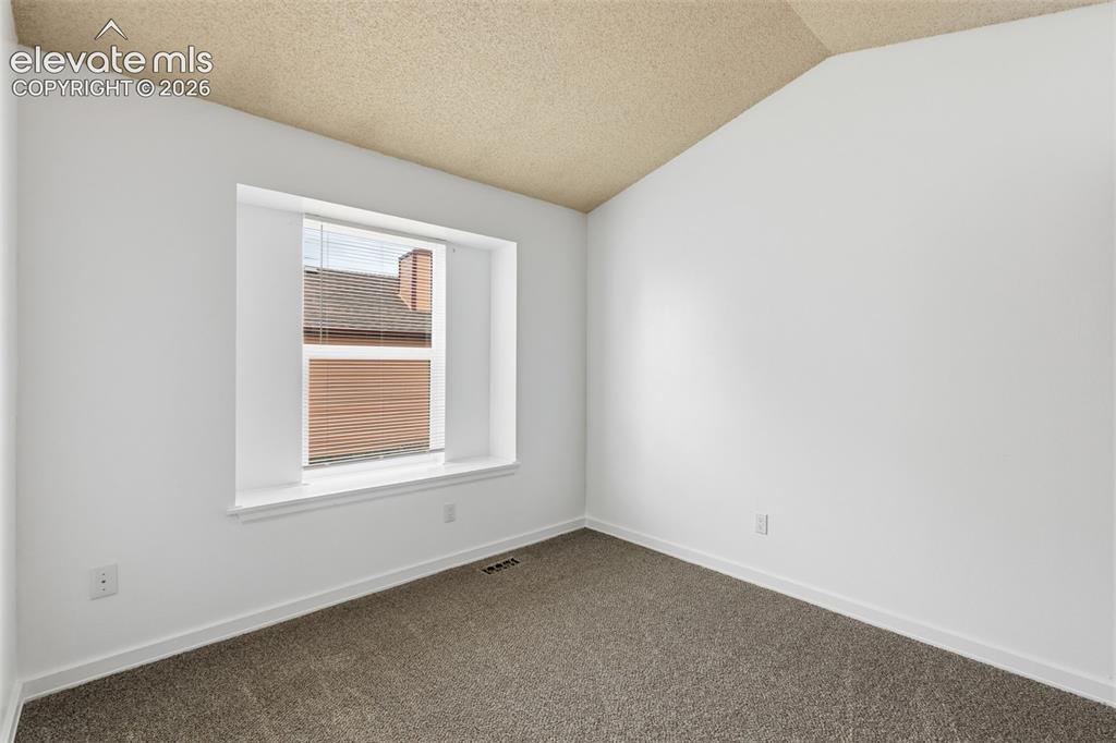 Image 38 of 43: Bright interior space featuring a window with white trim, vaulted ceiling,