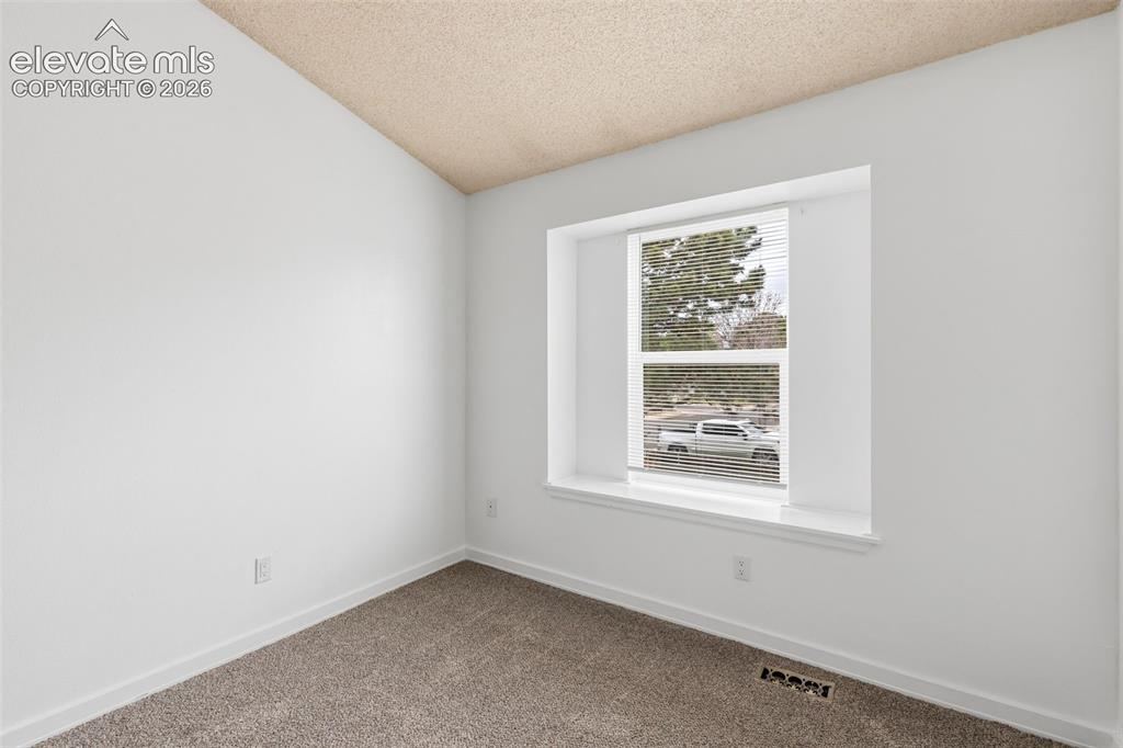 Image 39 of 43: Bright interior space featuring a textured ceiling, a single window with bl