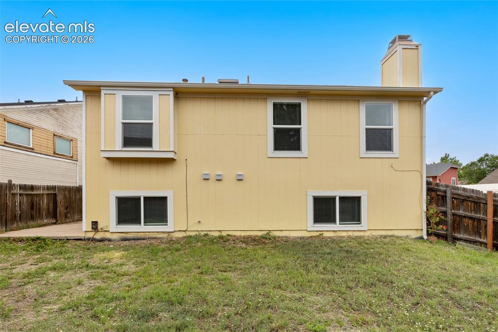 Image 42 of 43: Rear exterior featuring light yellow siding, multiple windows, a bay window
