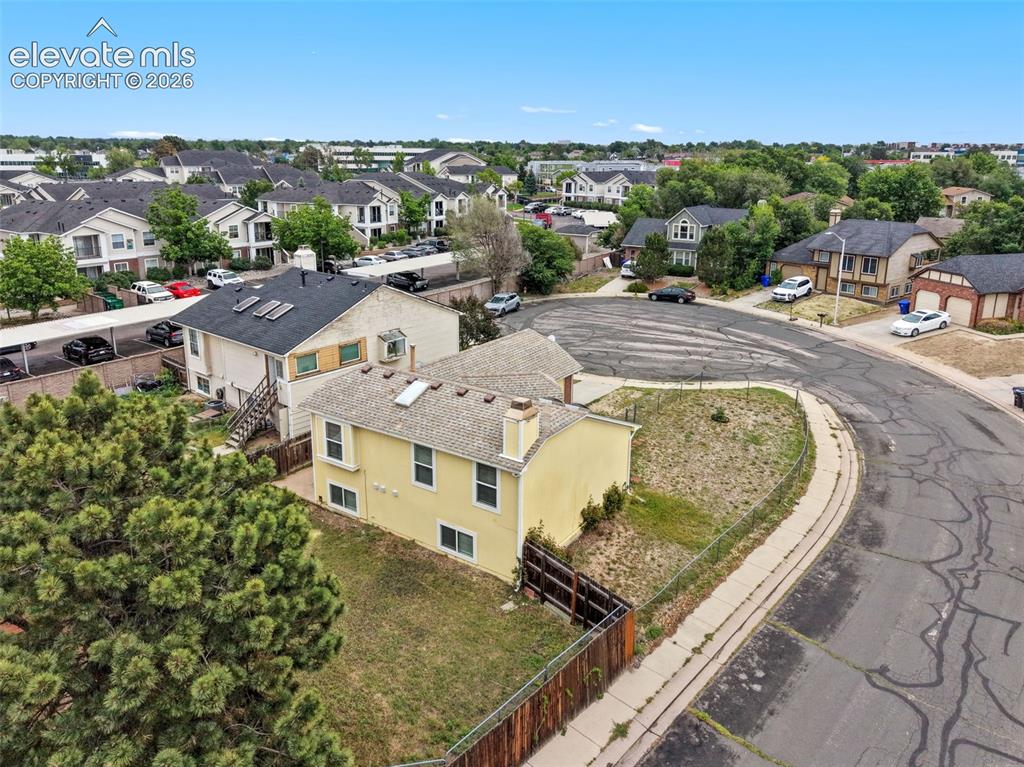 Image 6 of 43: Two-story residence featuring a wood fence, a grassy yard, and multiple win