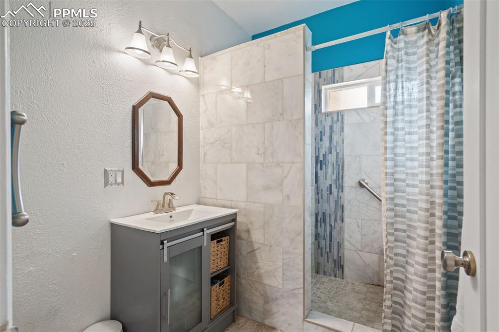 Image 15 of 30: Bathroom in main home with marble tile walk-in shower with built in bench.