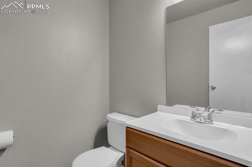 Image 11 of 28: Bathroom featuring toilet, vanity, and a textured wall