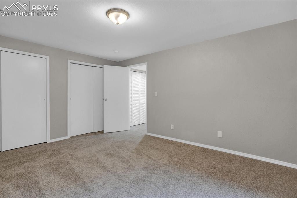 Image 12 of 28: Unfurnished bedroom with multiple closets, carpet, and baseboards