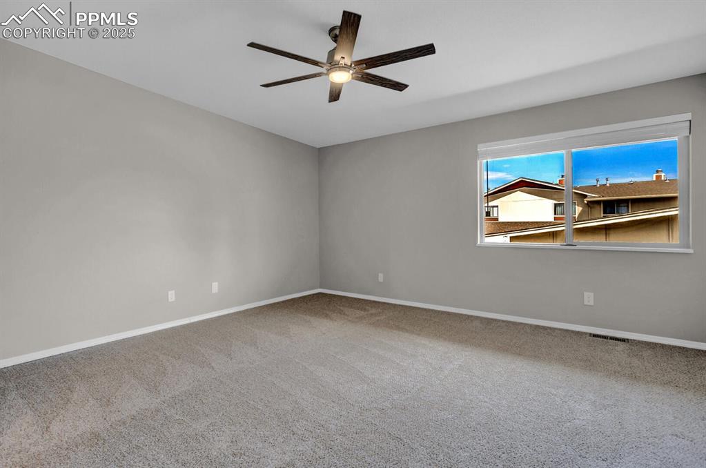 Image 13 of 28: Spare room with ceiling fan, carpet floors, and baseboards