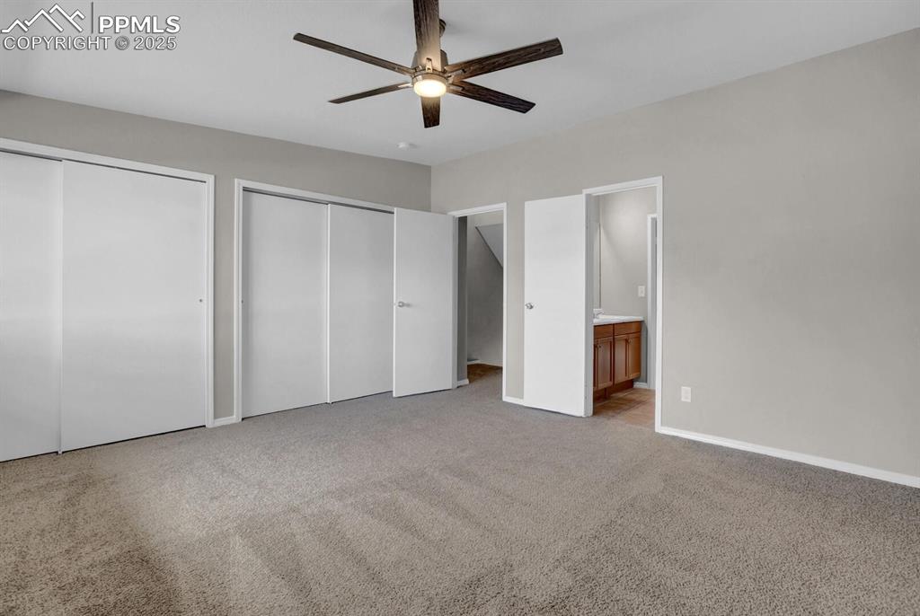Image 14 of 28: Unfurnished bedroom featuring two closets, carpet flooring, connected bathr