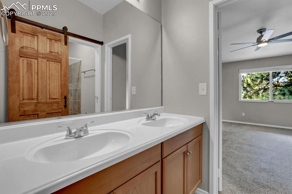 Image 16 of 28: Bathroom featuring ceiling fan, double vanity, and baseboards