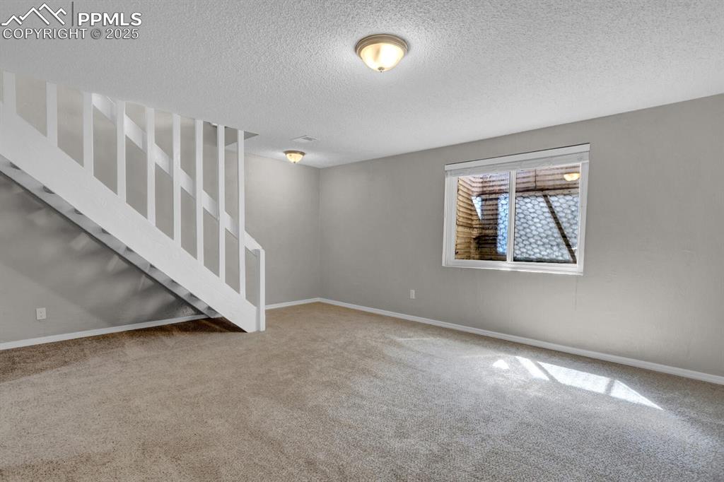 Image 19 of 28: Basement with carpet floors, a textured ceiling, and baseboards