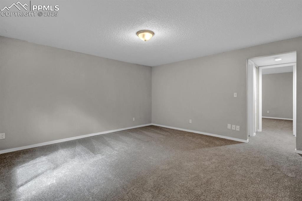 Image 20 of 28: Carpeted empty room featuring a textured ceiling and baseboards