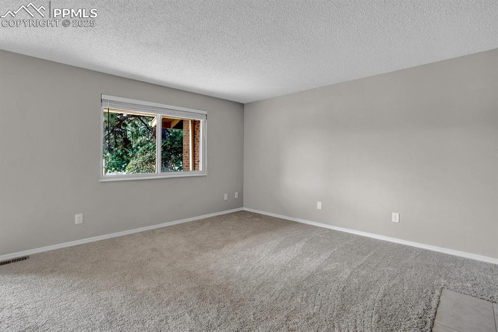 Image 6 of 28: Unfurnished room featuring a textured ceiling, carpet, and baseboards