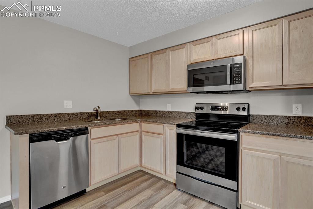 Image 7 of 28: Kitchen with appliances with stainless steel finishes, light brown cabinets