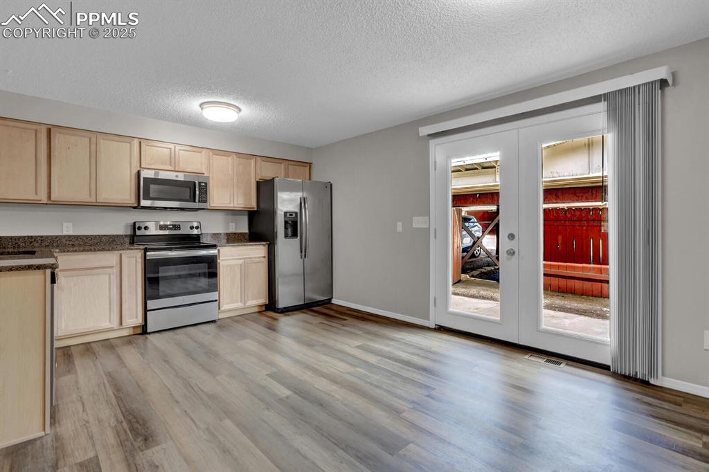 Image 8 of 28: Kitchen with stainless steel appliances, light brown cabinets, light wood-s