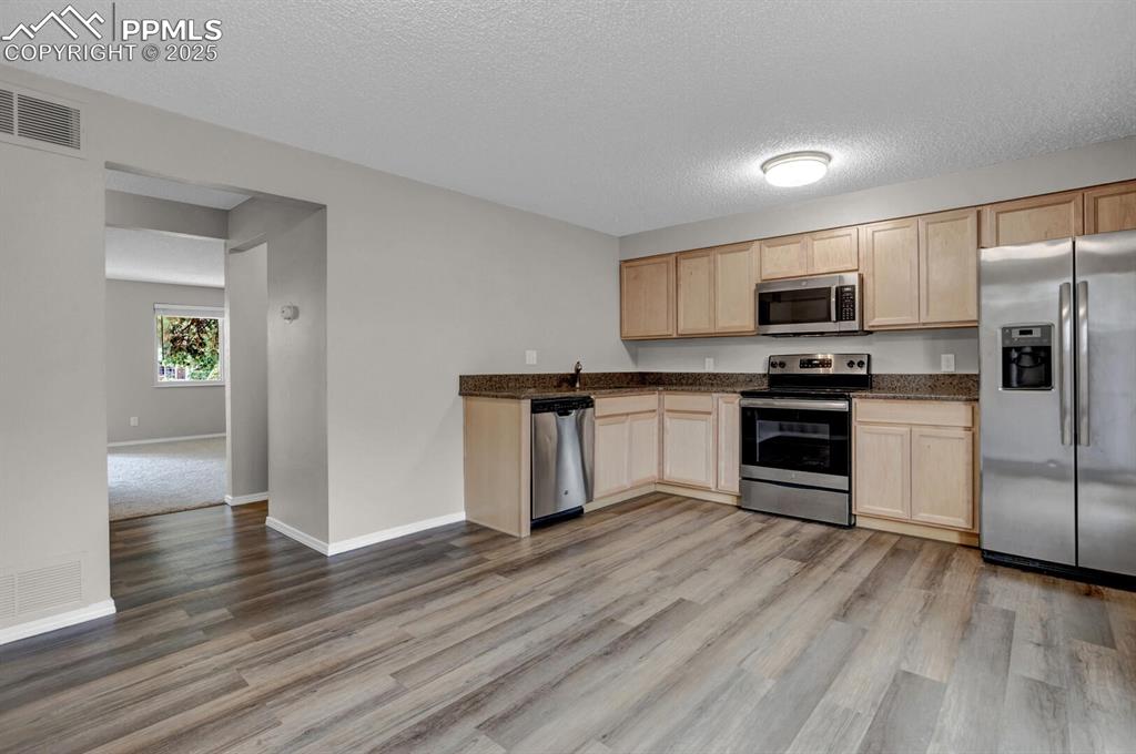 Image 9 of 28: Kitchen featuring stainless steel appliances, light brown cabinetry, light
