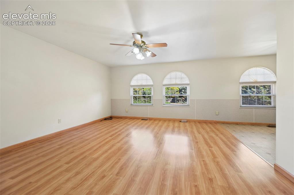 Image 10 of 50: Spacious room featuring wood-finish flooring, three arched top windows, and