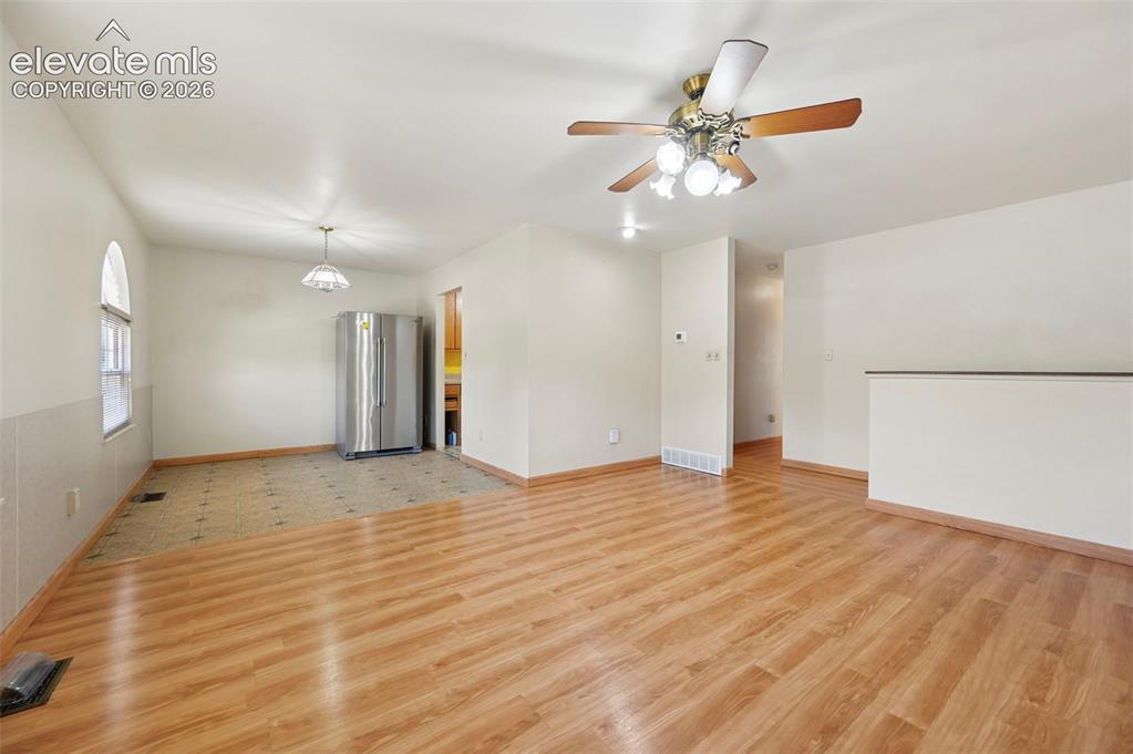 Image 12 of 50: Wood-finish flooring, half-wall partition, ceiling fan with integrated ligh