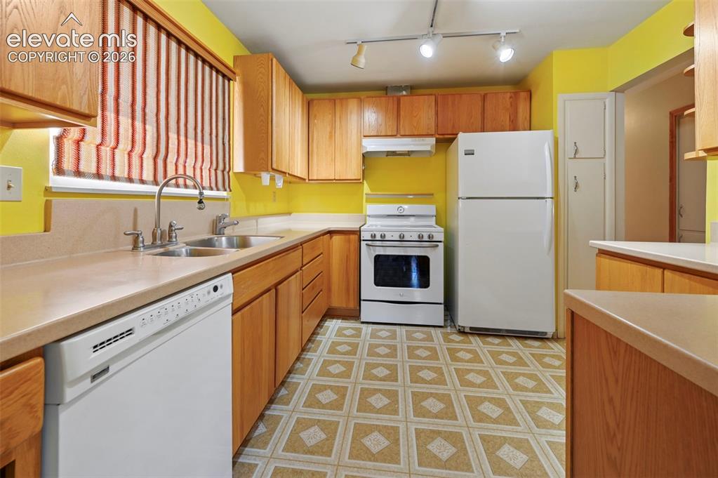 Image 16 of 50: U-shaped kitchen with wood-finish cabinetry, light-toned countertops, and a