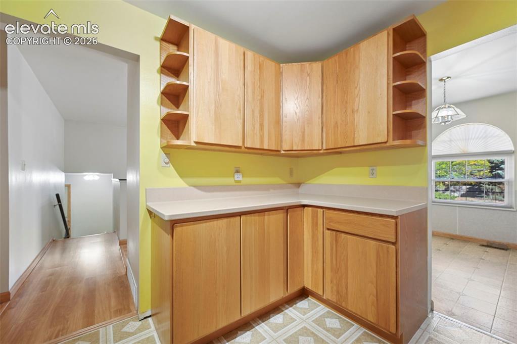 Image 17 of 50: Corner cabinetry with natural wood finish, light-toned countertops, and ope