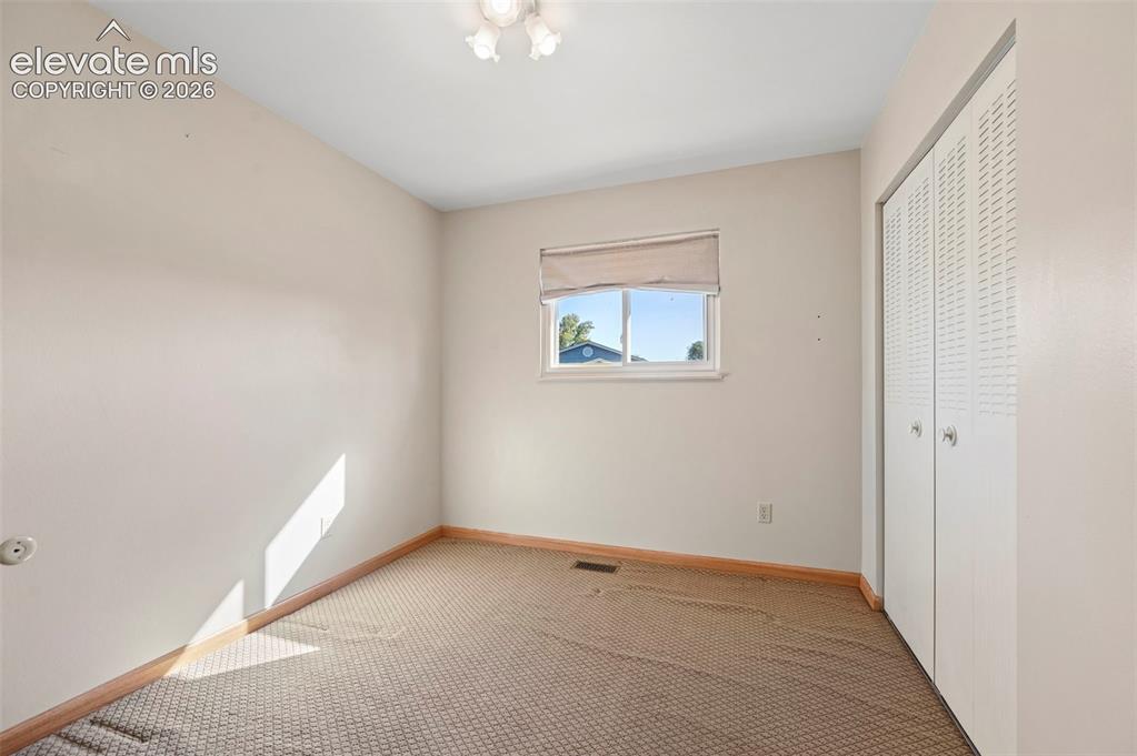 Image 23 of 50: Window with roller shade, carpeted flooring, wood-finish baseboards, and bi