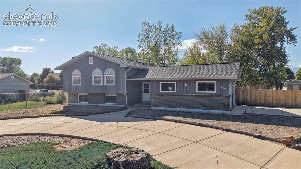 Image 3 of 50: Split-level residence featuring gray siding, a brick-finish foundation, and