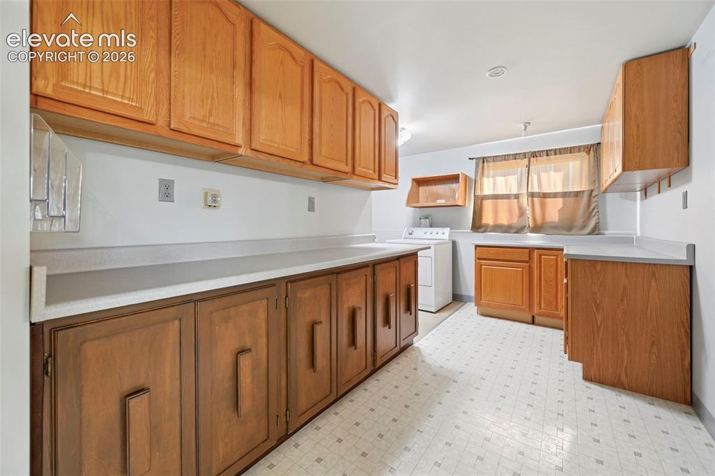 Image 34 of 50: Extensive wood cabinetry, ample counter space, integrated laundry area, win