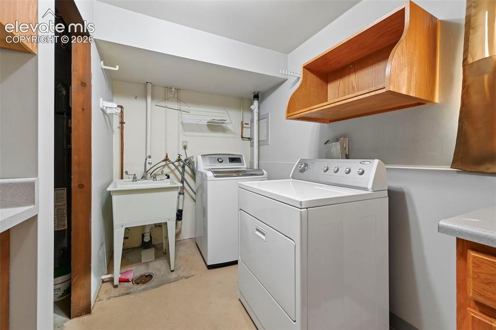 Image 35 of 50: Laundry area featuring a utility sink, open shelving, and counter space