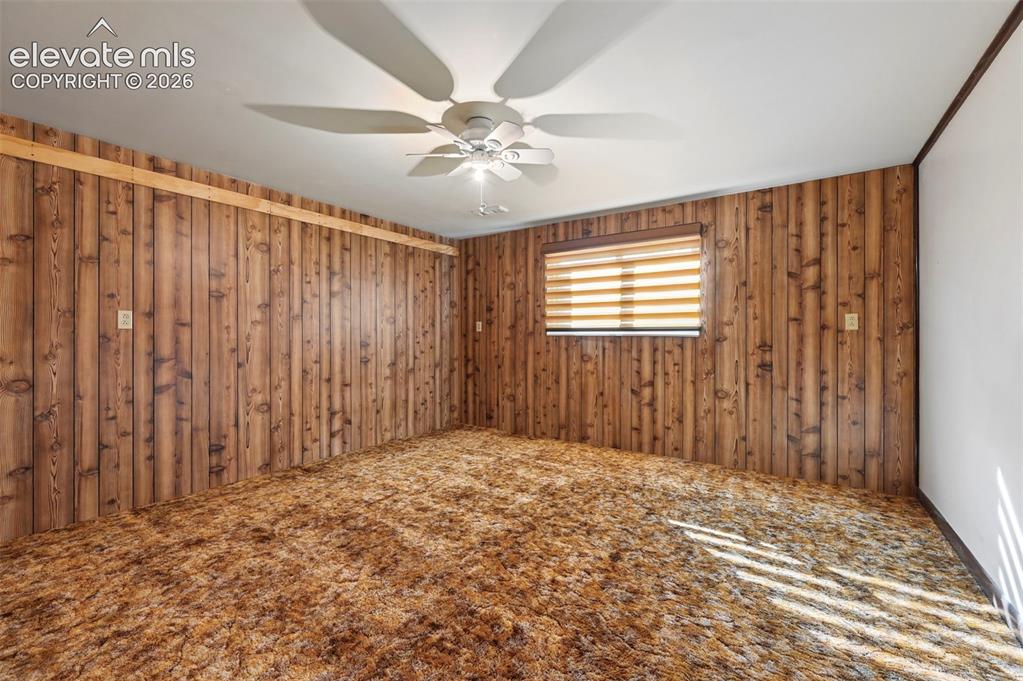 Image 36 of 50: Wood paneling walls, textured carpet flooring, window with blinds, ceiling