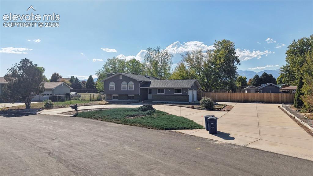 Image 4 of 50: Split-level residence featuring gray siding, a dual-car garage, and a concr