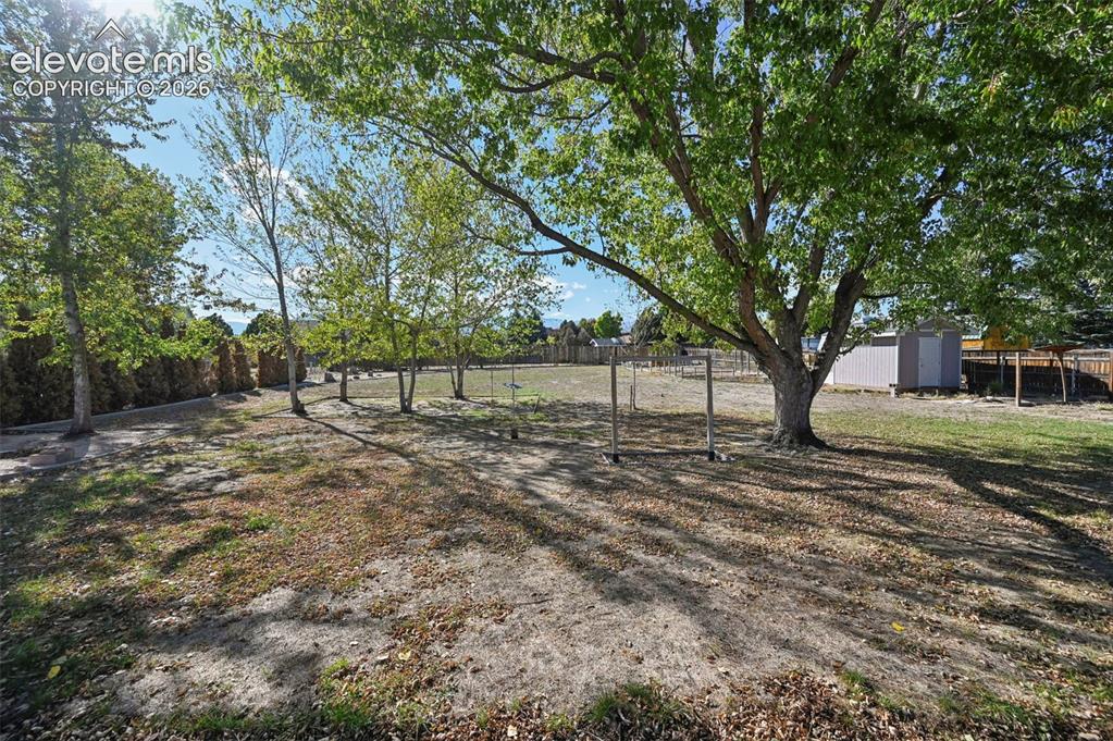 Image 40 of 50: Expansive yard featuring mature trees and a privacy fence