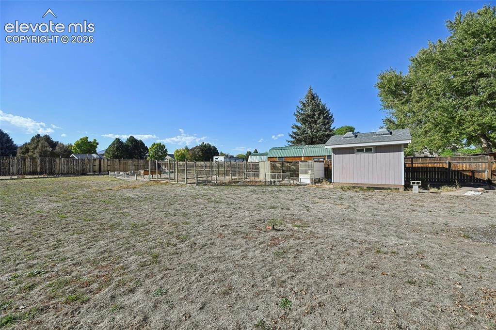Image 44 of 50: Expansive yard space featuring a detached storage shed, wood fencing, and m