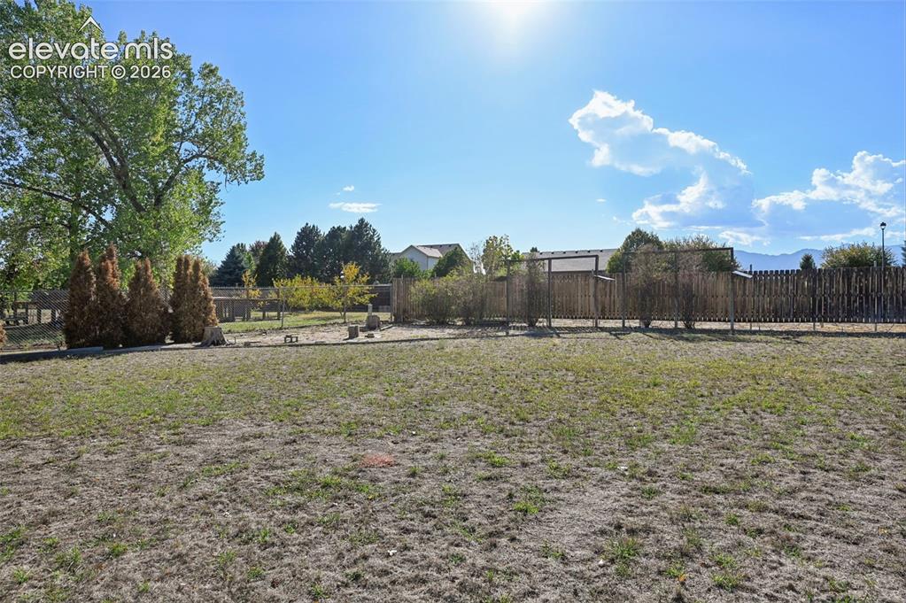 Image 45 of 50: Expansive outdoor space featuring a wood fence, mature trees, and landscapi