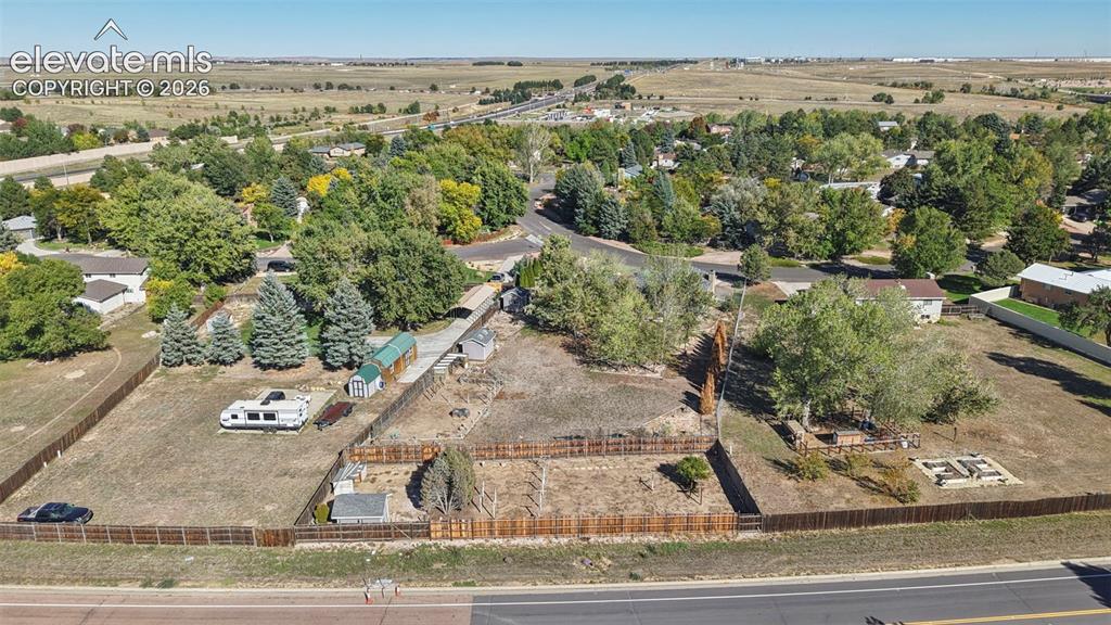 Image 49 of 50: Fenced property with expansive open space, mature trees, and storage sheds