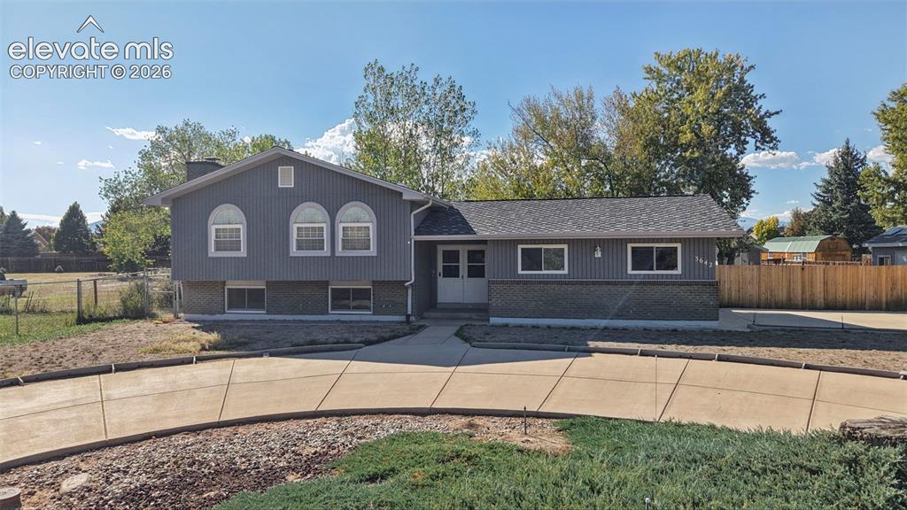 Image 5 of 50: Gray siding exterior with a dark shingle roof and a concrete driveway