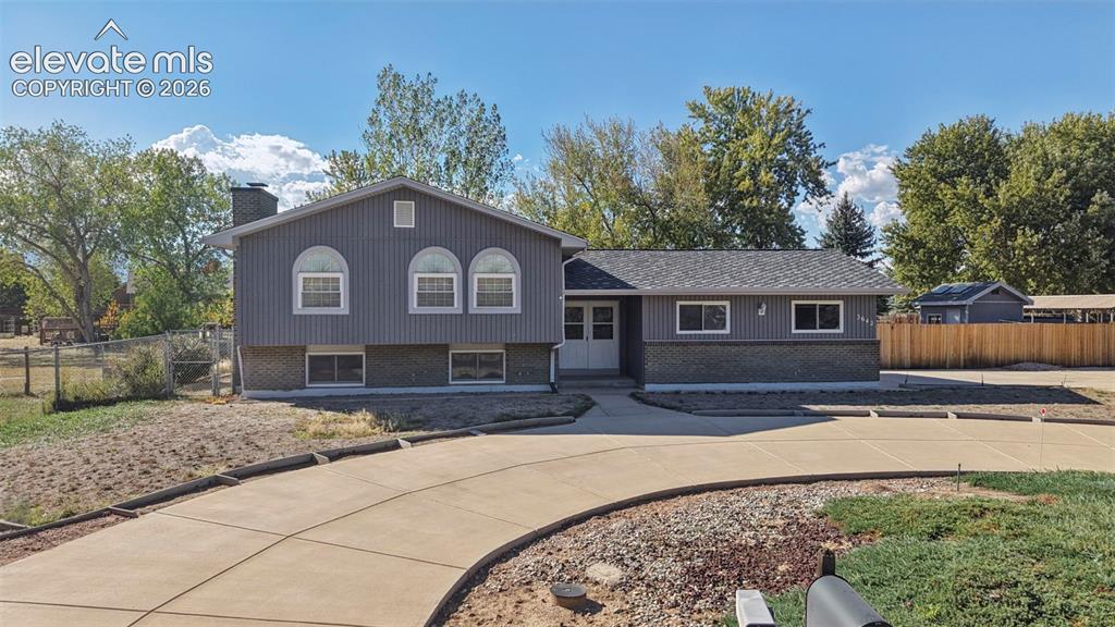 Image 6 of 50: Exterior siding with brick accents, arched windows, and a paved driveway