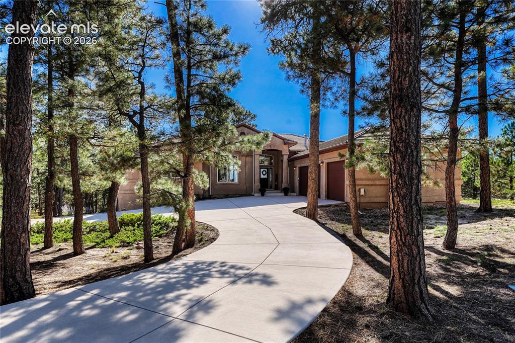 Image 1 of 49: Stucco exterior featuring a covered entryway with stone-column accents, a m