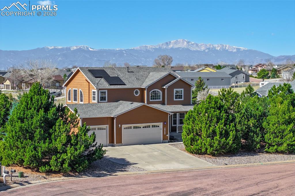 Caption: Traditional Home featuring roof mounted solar panels, driveway, a mountain view, an attached garage,