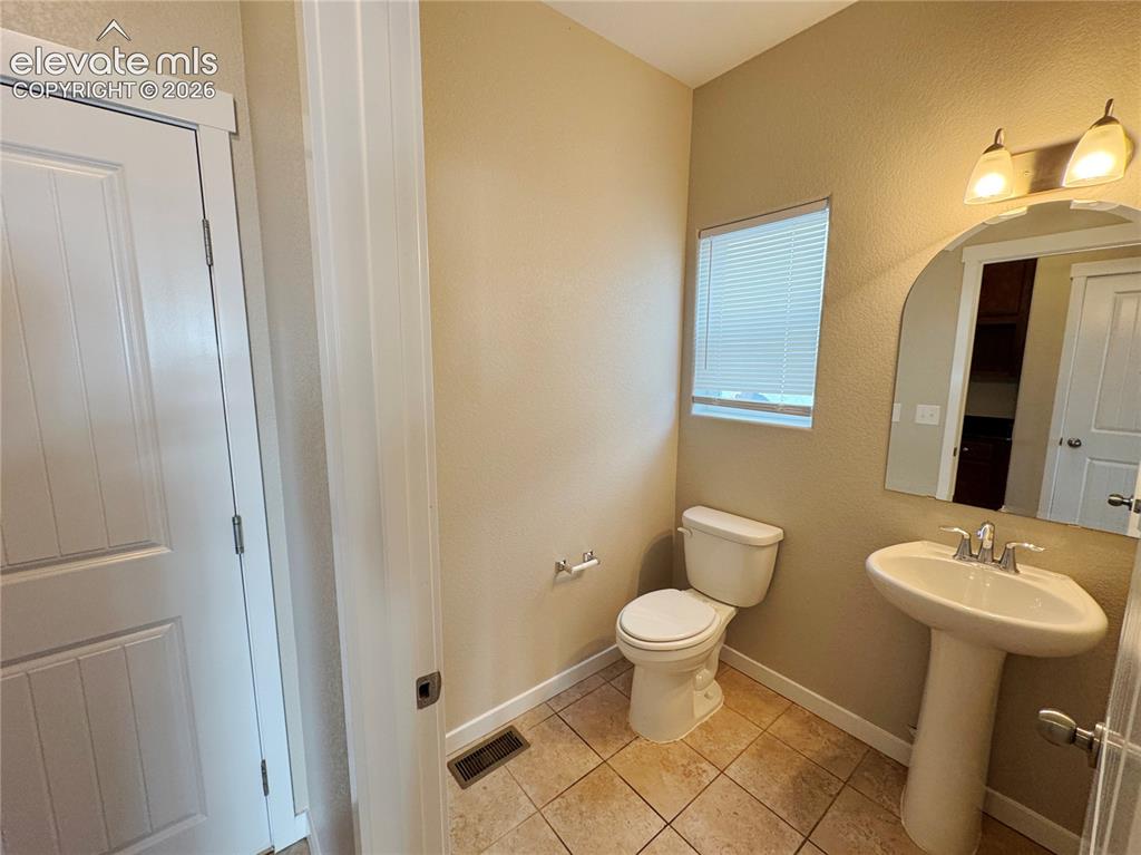 Image 15 of 42: Pedestal sink with chrome faucet, arched wall mirror, two-light fixture, an
