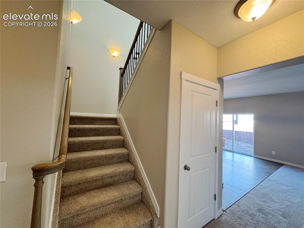Image 16 of 42: Staircase featuring a wood handrail with metal balusters, carpeted treads, 