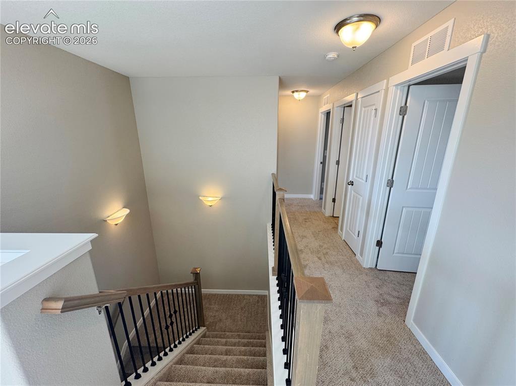 Image 23 of 42: Hallway featuring carpeted flooring, two-panel interior doors, wall-mounted