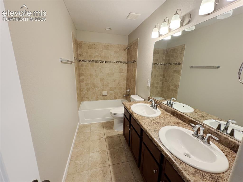 Image 25 of 42: Dual-sink vanity with stone-finish countertop, tile-surround bathtub, ceram